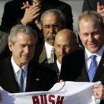 With hundreds of Red Sox Nation citizens in attendance on the south lawn, President George W. Bush praises the team spirit and winning style of the 2004 World Champions during a White House ceremony. Fall Classic hero and Bush supporter Curt Schilling gives the former owner of the Texas Rangers a white baseball jersey emblazoned with the forty-third Chief Executive's name and the number 43.