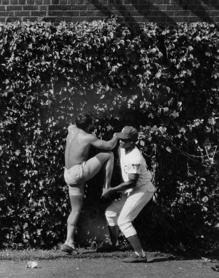 Cubs outfielder Willie Smith gives a boost to a fan who fell from the bleachers