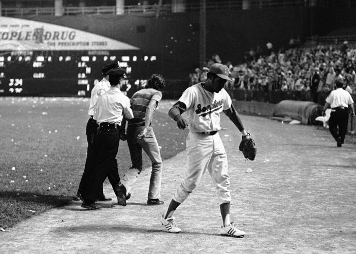 Dave Nelson of the Washington Senators makes his way toward the dugout as fans begin to storm the field in Washington, Oct. 1, 1971. The Senators forfeited the game to the Yankees due to fan actions. (AP Photo/Jim Palmer)